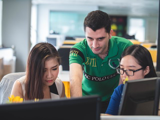 educational technology - teacher pointing at screen with two asian girls